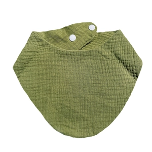 Detailed macro of grass green cotton crepe baby bib with white snap closures