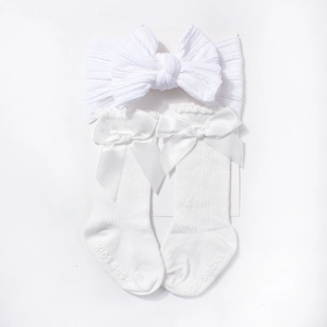 Detailed view of white baby headband and matching socks with elegant large bows