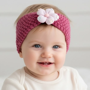Detailed close-up of a cozy pink knitted baby headband with a 3D fabric flower accent