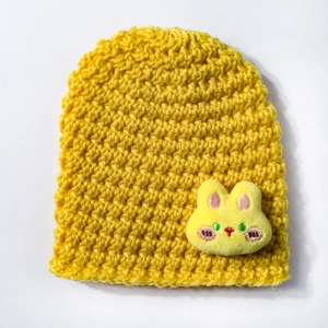 Detail of yellow knit baby hat with a cute 3D bunny ornament and soft texture