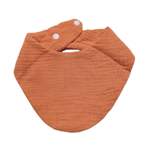 Detail of the breathable muslin cotton texture and adjustable white resin snaps on baby bib