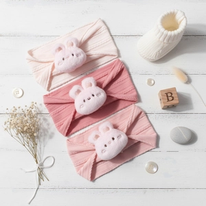 Detailed set of three pink knitted baby headbands featuring cute embroidered plush bunny ears