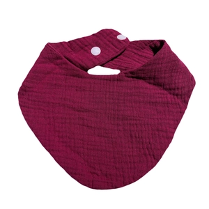 Detail of burgundy cotton gauze baby bib featuring dual snap fasteners and soft texture