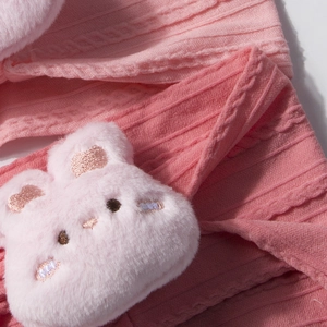 Vue détaillée du bandeau tricoté rose pour bébé avec lapin en peluche 3D et maille torsadée