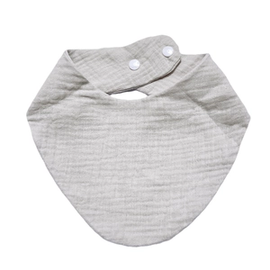 Detail of soft organic cotton muslin baby bib with adjustable snap buttons and crinkle texture