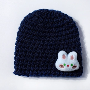 Close-up of dark blue knit baby hat featuring a soft white plush bunny patch detail