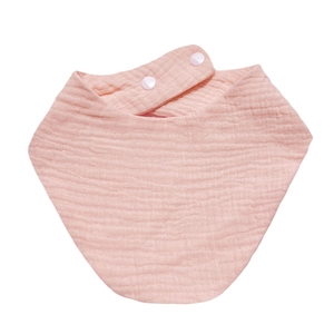 Detail view of pink cotton muslin baby bib with double snap buttons and soft texture