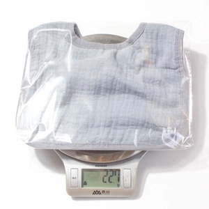 Mesure du poids d'un bavoir en gaze de coton gris emballé affichant 22,1g sur la balance