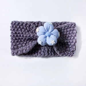 Close-up of baby knit headband with purple yarn texture and blue embroidered flower detail