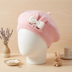 Pink rabbit knitted baby beret with cute bow and embroidery on a white mannequin