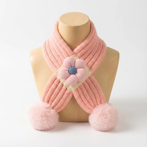 Détail d'une écharpe en tricot pour bébé avec fleur en velours et pompons en fausse fourrure