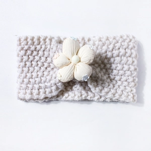 Detail of off-white knitted baby headband featuring a soft 3D fabric flower decor