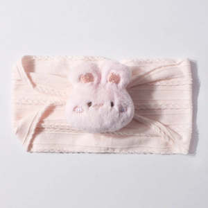 Détail d'un bandeau rose pour bébé avec un lapin en peluche et une texture en tricot