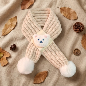 Detail of baby bear knitted scarf in beige yarn with plush bear head and fuzzy pom-poms