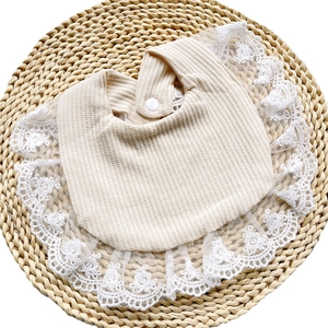 Macro detail of breathable waffle cotton baby bib with elegant white floral lace border