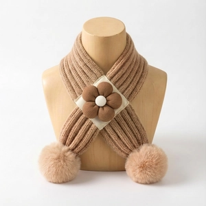 Détail d'une écharpe en tricot pour bébé camel avec fleur marron et pompons en fourrure
