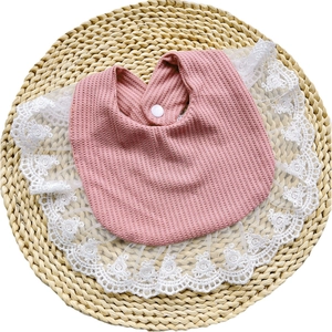 Detailed view of pink waffle cotton baby bib with white floral lace and resin snap button