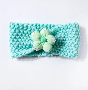 Detail of mint green knitted baby headband with decorative floral fabric accent