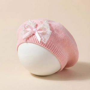 Béret en tricot rose pour bébé avec nœud en dentelle blanche et perles sur un support