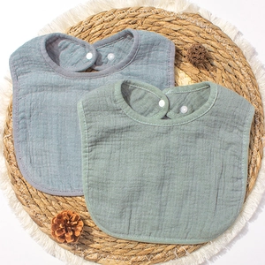 Bavoirs bébé en mousseline de coton bio bleu-gris et vert sauge sur tapis tressé