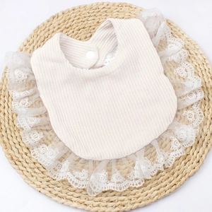 Detail of baby bib showing waffle cotton texture, lace edge, and snap button closure