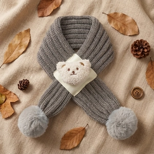 Detailed view of gray knit baby scarf with soft white bear patch and decorative pom-poms
