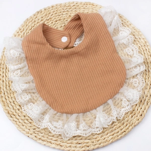 Detailed macro shot of brown waffle fabric baby bib with white lace embroidery