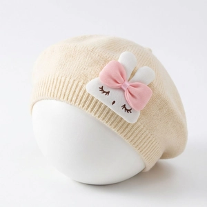 Detail view of cream knit baby beret with a 3D bunny plush and pink silk bow