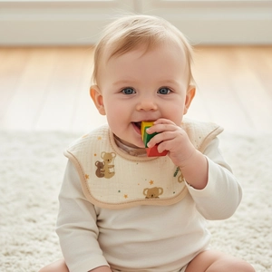 Detail of soft cotton baby bib with koala print on a white long sleeve onesie
