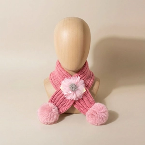 Détail d'une écharpe en maille rose pour bébé avec fleur en tulle et pompons doux