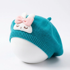 Detailed knit texture of a cyan baby beret with a cute white rabbit embroidery patch