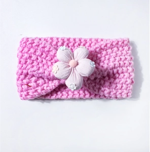 Détail du bandeau tricoté rose pour bébé avec une grande fleur en tissu multicouche
