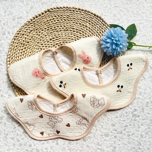 Three-pack cotton baby bibs set featuring bunny and cherry prints on a woven mat