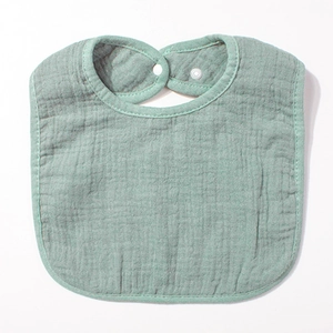 Détail d'un bavoir bébé en gaze de coton vert haricot avec bouton-pression blanc