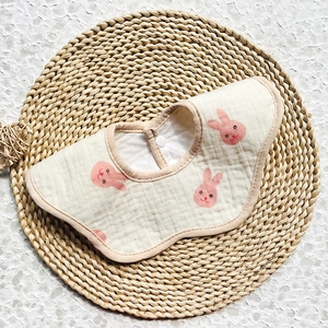Detail of petal-shaped baby bib in soft cotton gauze with cute pink rabbit prints