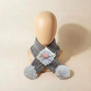 Détail d'une écharpe en tricot gris pour bébé avec fleur violette et pompons en fourrure