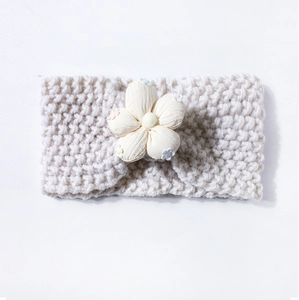 Gros plan d'un bandeau en tricot pour bébé avec grande fleur et texture laine douce