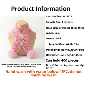 Close-up of pink knitted baby scarf with bow tie and pom-poms for winter warmth