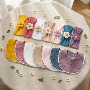 Detail showing knit floral headbands and cotton bibs with pompom trim in Morandi colors