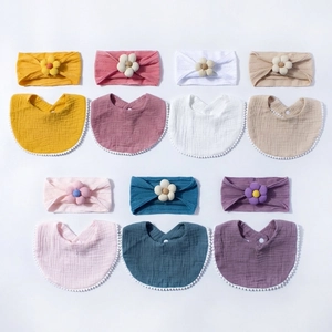 Detail view of 7-color baby muslin bibs and flower headband sets on a clean white background