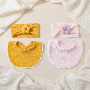 Detail of baby floral headbands and cotton bibs with pompom trim in yellow and pink