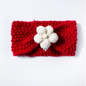 Détail d'un bandeau en tricot rouge avec une grande fleur blanche pour bébés et enfants