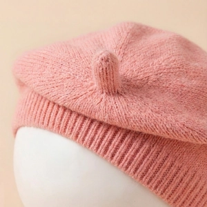 Close-up of pink knitted baby beret showing soft textured yarn and ribbed edge details
