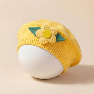 Detail of yellow knitted baby beret with 3D flower and green leaves for newborns
