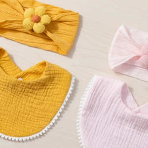 Newborn baby muslin bib and flower headband set in pink and yellow on wooden backdrop