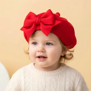 Détail du béret en tricot rouge pour bébé avec un grand nœud et une finition côtelée
