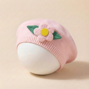 Detailed texture of pink knitted baby beret featuring 3D floral accent and ribbed edge