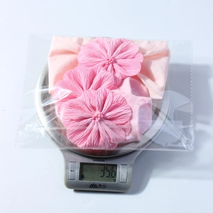 Nahaufnahme von rosa Baby-Stirnband und Socken-Set auf Waage mit ca. 35,6 Gramm Gewicht