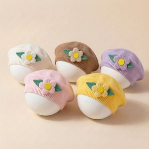 Detail of five assorted knitted baby berets with 3D plush flower and leaf decorations