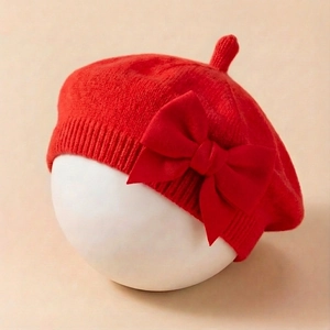 Détail d'un béret en tricot rouge pour bébé avec un grand nœud et une texture douce